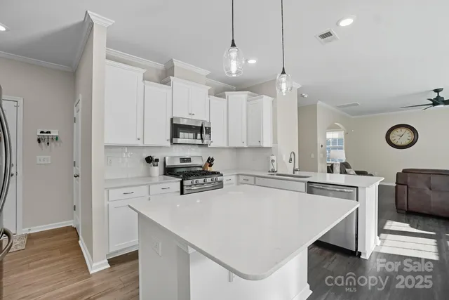 a kitchen with a stove a refrigerator a sink and white cabinets with wooden floor