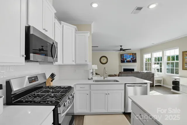 a kitchen with stainless steel appliances a stove a sink a microwave and cabinets
