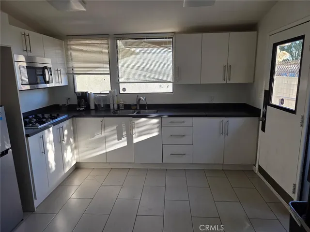 a kitchen with granite countertop a stove a sink and a microwave