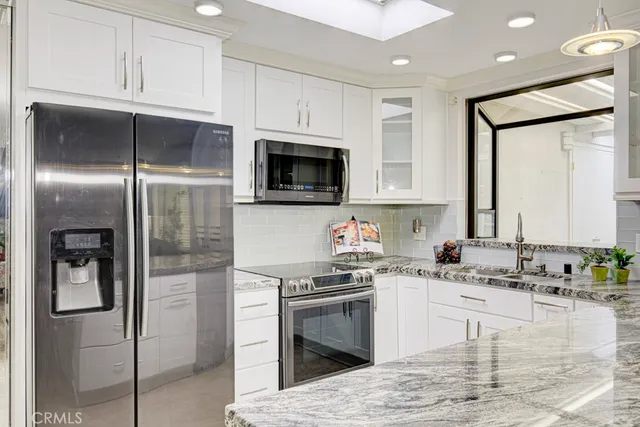 a kitchen with stainless steel appliances granite countertop a refrigerator a stove and a sink with wooden floor