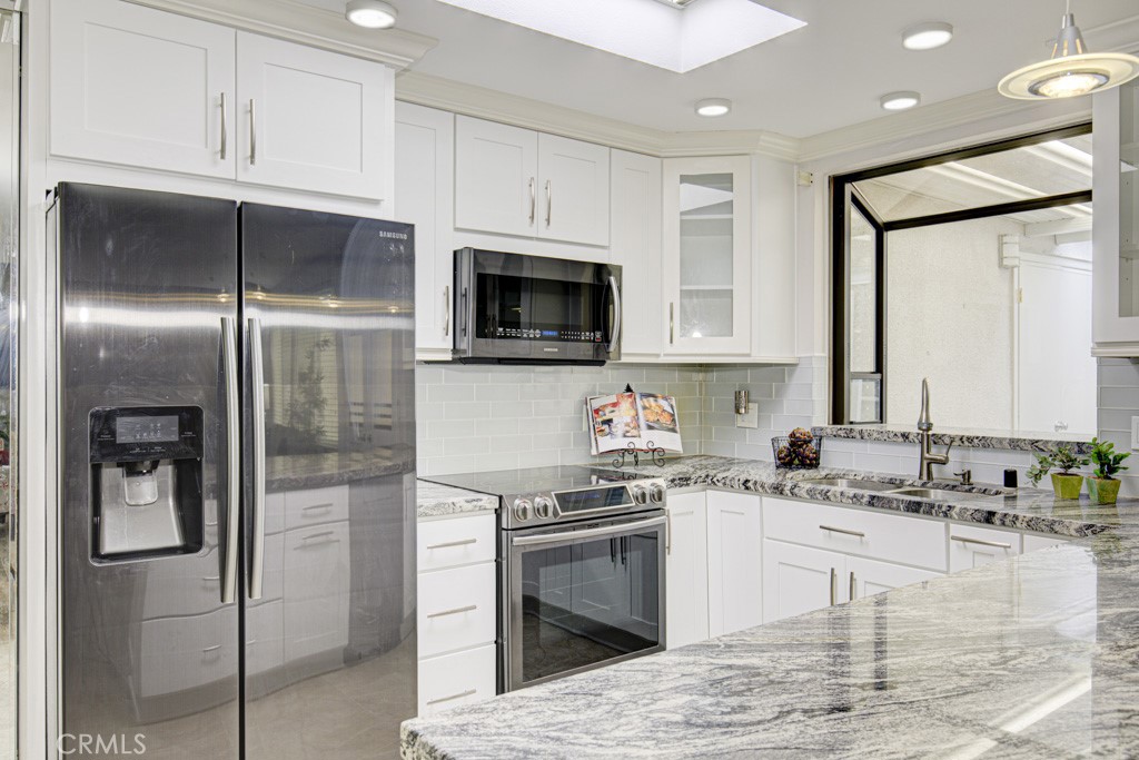 245 Calle Aragon, Unit C Laguna Woods, CA 92637 - Photo 2 of 32 a kitchen with stainless steel appliances granite countertop a refrigerator a stove and a sink with wooden floor