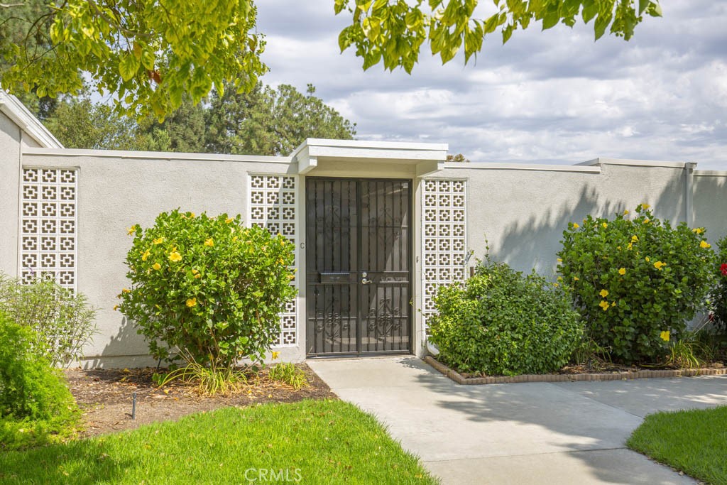 245 Calle Aragon, Unit C Laguna Woods, CA 92637 - Photo 26 of 32 a front view of a house with a yard and garage
