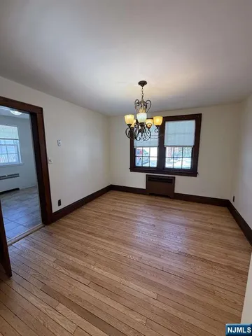an empty room with wooden floor and chandelier