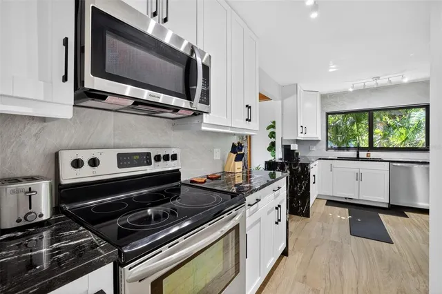 a kitchen with stainless steel appliances a stove a microwave a sink and cabinets