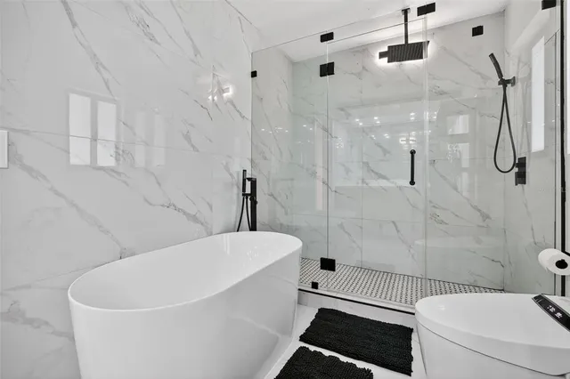 a white bath tub sitting next to a white toilet and a shower