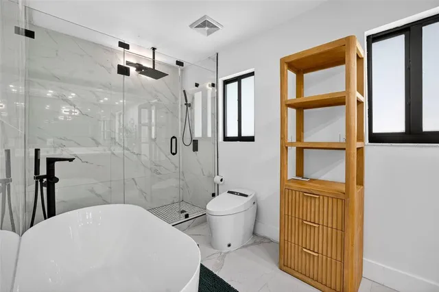 a bathroom with a toilet a sink a shower and a window