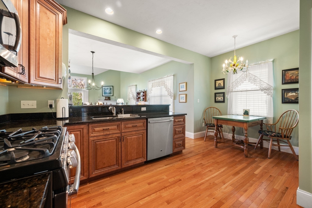 96 Walden Way, Unit 52 Milford, MA 01757 - Photo 3 of 23 a kitchen with stainless steel appliances granite countertop a stove a sink dishwasher a dining table and chairs with wooden floor