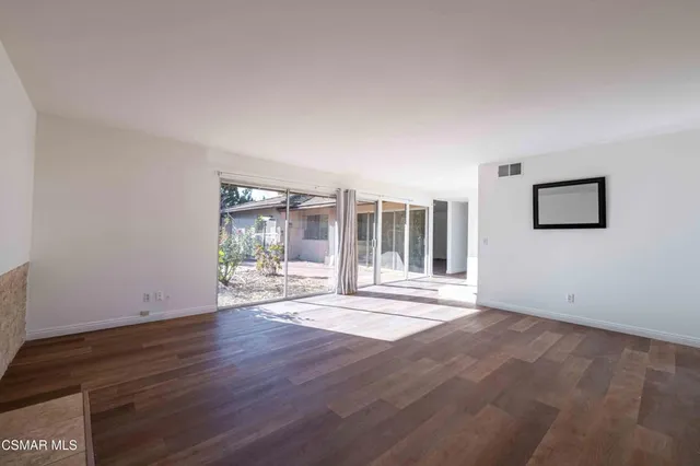 a view of a big room with wooden floor and windows