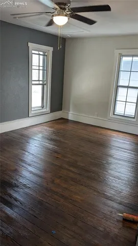 a view of an empty room with wooden floor and a window