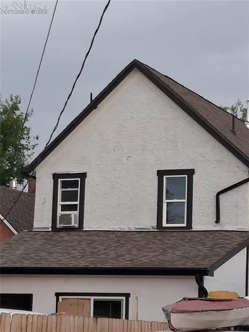 a view of a white house with large trees next to a road