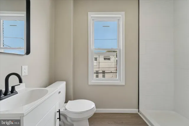 a bathroom with a toilet sink vanity tub and mirror