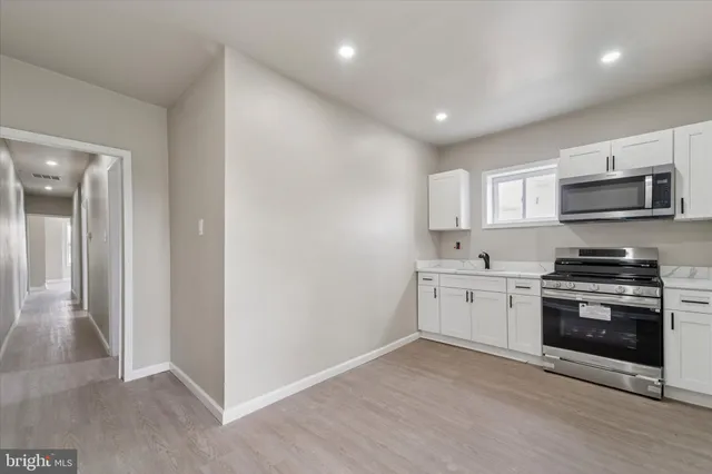 a kitchen with granite countertop white cabinets and stainless steel appliances