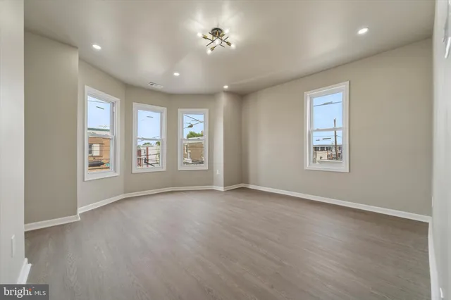 a view of an empty room with a window and wooden floor