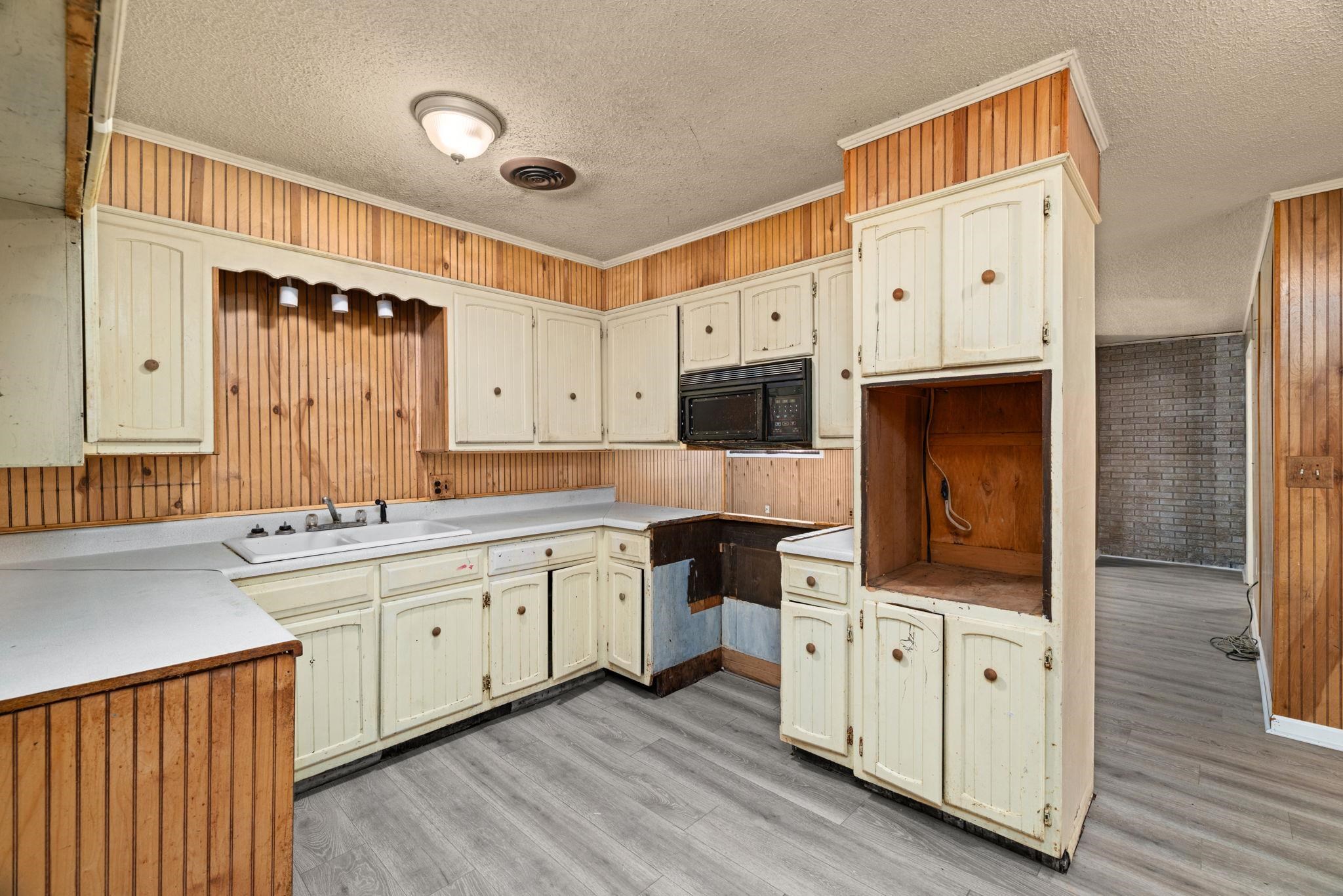 60116 Seminole Road Smithville, MS 38870 - Photo 14 of 38 Kitchen featuring wood-finish wall paneling, painted cabinetry, and wood-finish flooring