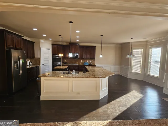 a view of kitchen with refrigerator stove and wooden floor