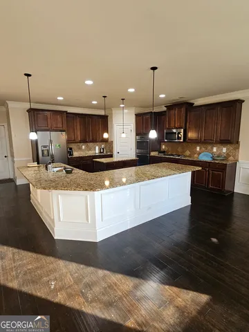 a large kitchen with kitchen island granite countertop wooden cabinets a sink and dishwasher