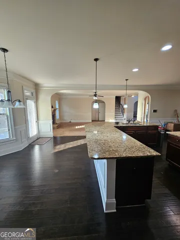 a view of a room with wooden floor staircase and kitchen view