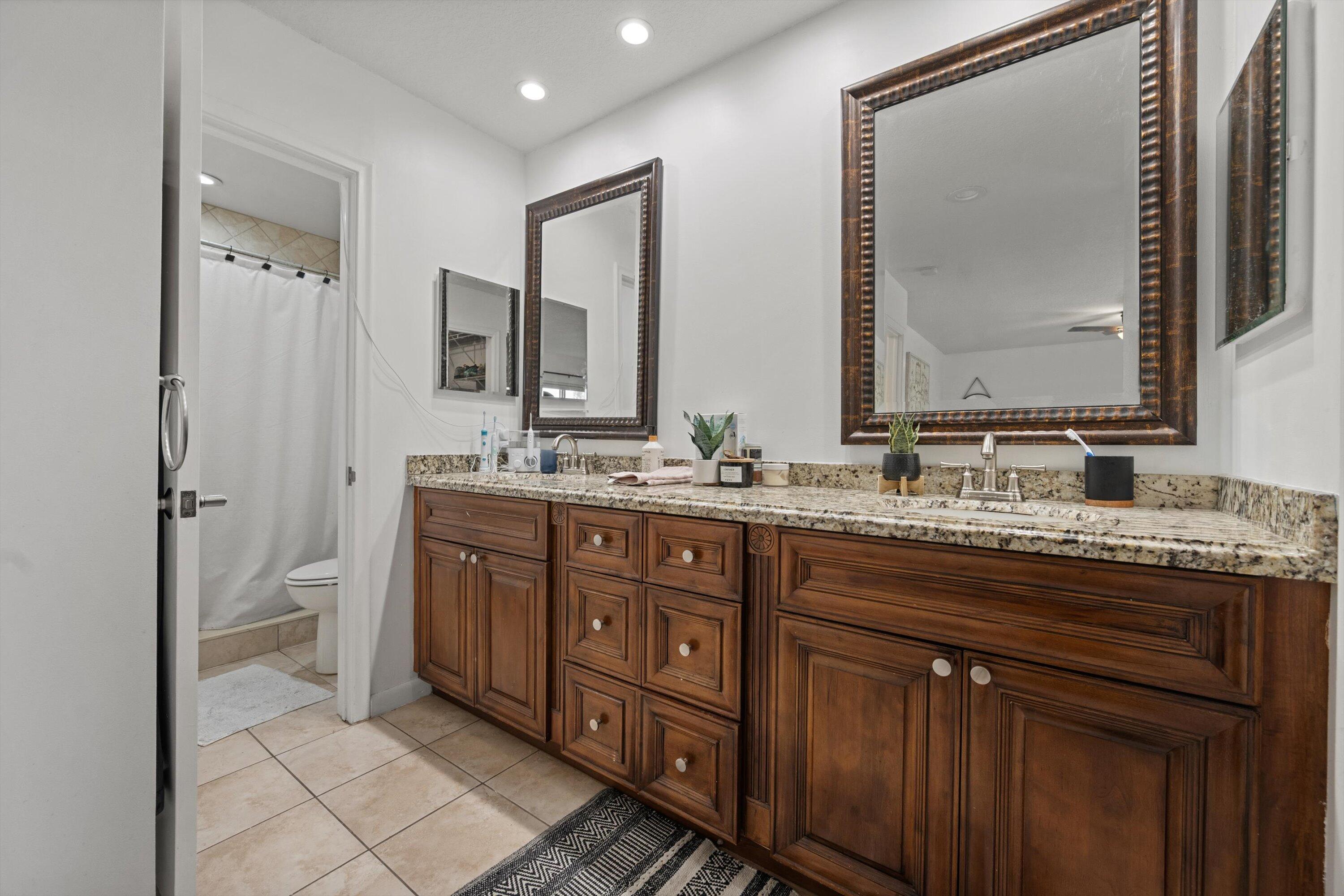404 Pine Tree Court, Unit 6 Atlantis, FL 33462 - Photo 14 of 26 a bathroom with a granite countertop double vanity sink and a mirror