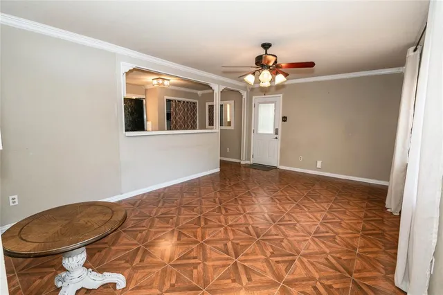 a view of a room with a chandelier fan and wooden floor