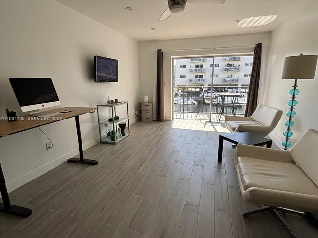 a work room with furniture wooden floor and a flat screen tv