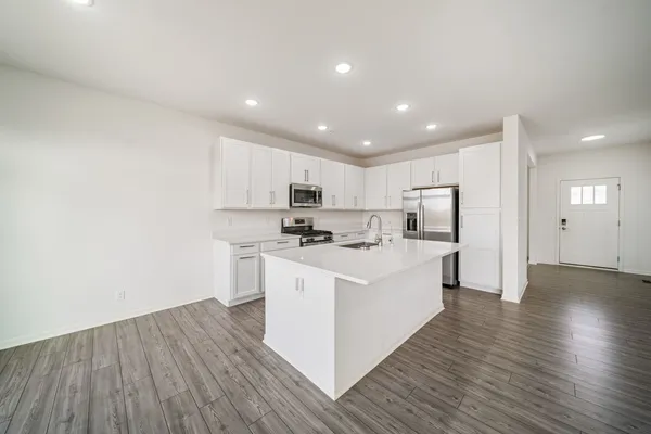 a large white kitchen with wooden floor and a sink