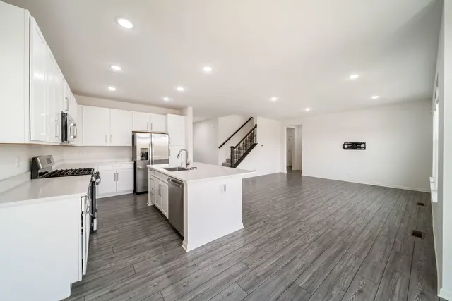 a kitchen with a sink stainless steel appliances wooden floor and a window