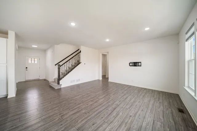 a view of an empty room with wooden floor and stairs