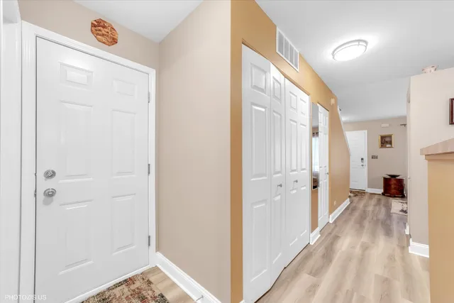 a view of a hallway with wooden floor and a bathroom