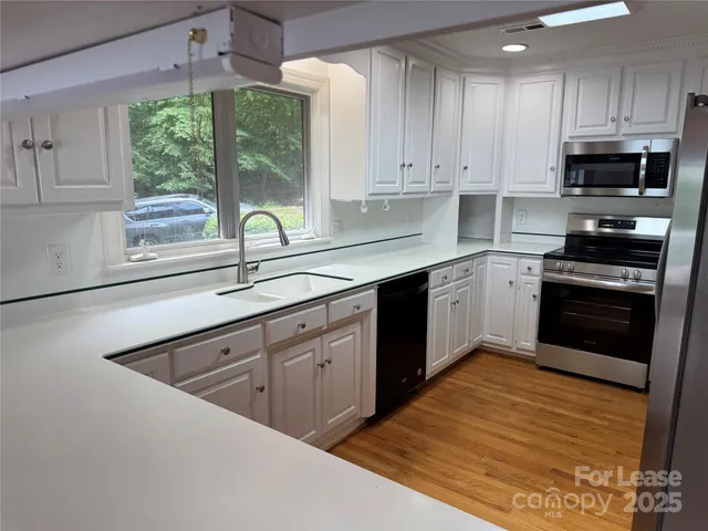 a kitchen with stainless steel appliances granite countertop a sink a stove and a refrigerator