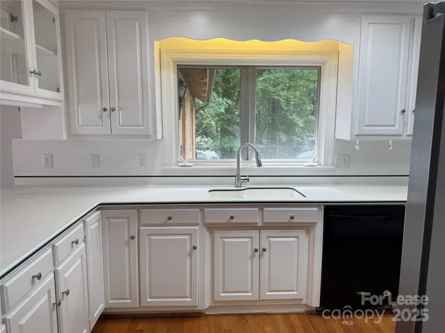 a kitchen with granite countertop white cabinets and a window