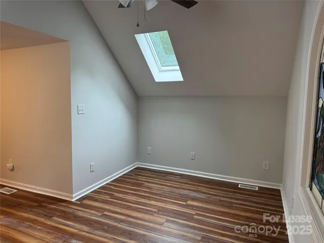 a view of an empty room with wooden floor fireplace and a window