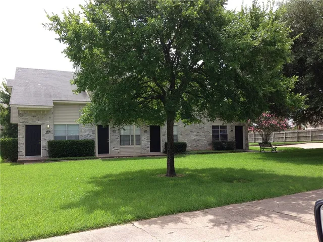 a front view of a house with a garden and trees