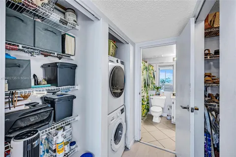 a utility room with dryer washer and a view of living room
