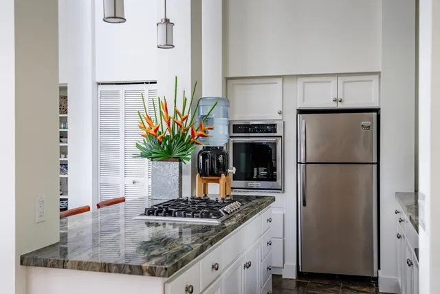 a kitchen with stainless steel appliances granite countertop a refrigerator a stove and a sink