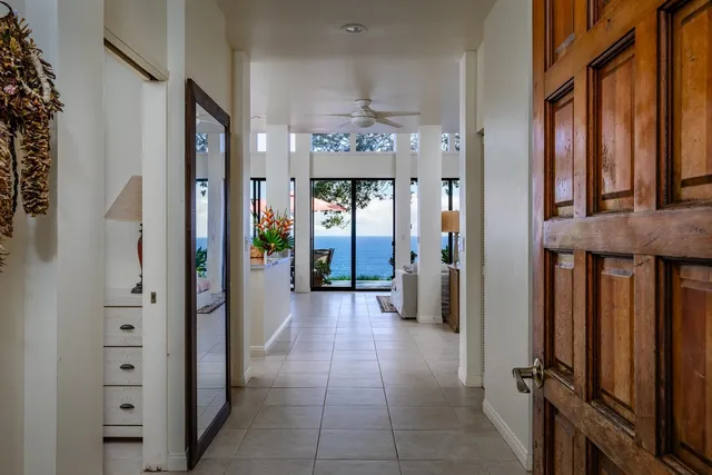 a dining table with a large window and potted plants on the dresser