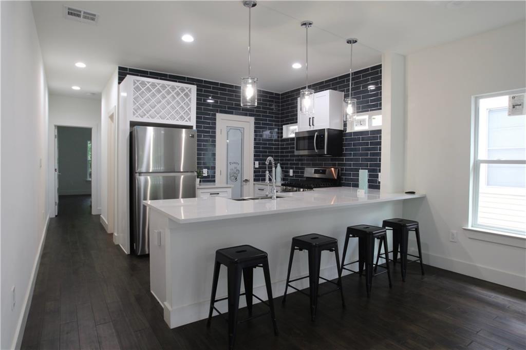 705 Harris Avenue, Unit A Austin, TX 78705 - Photo 6 of 33 a kitchen with stainless steel appliances granite countertop a refrigerator a stove top oven and a dining table with wooden floor