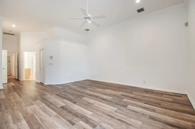 a view of empty room with wooden floor and ceiling fan