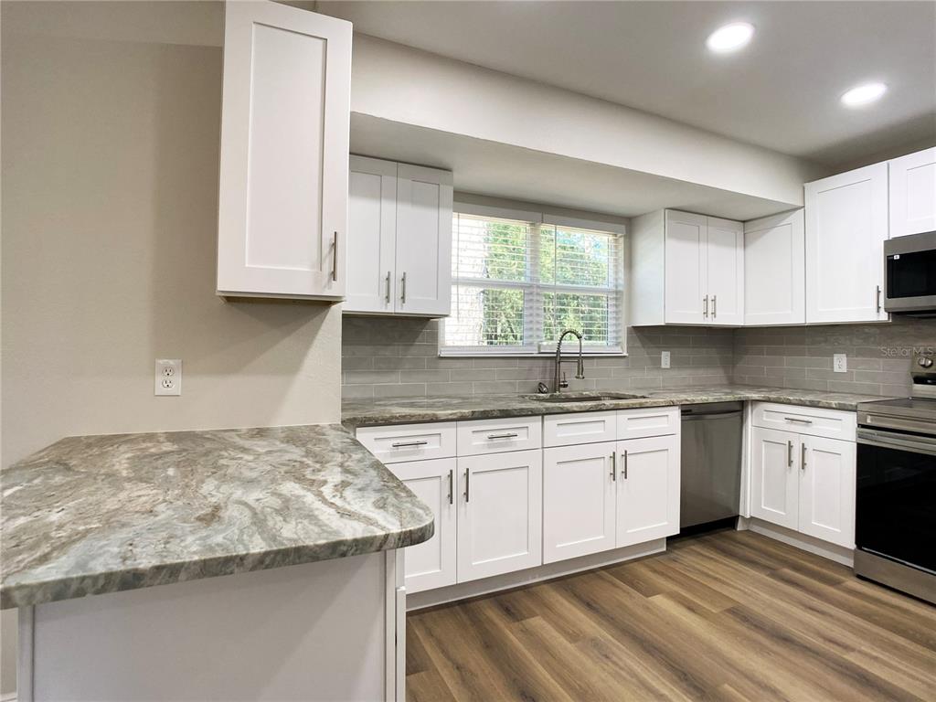 18 Midway Court Ocala, FL 34472 - Photo 22 of 38 a kitchen with granite countertop stainless steel appliances white cabinets granite counter tops and a window