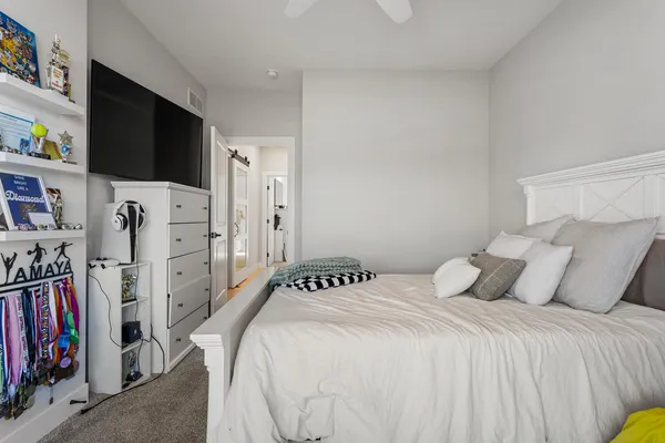 a bedroom with a bed a flat screen tv and a book shelf