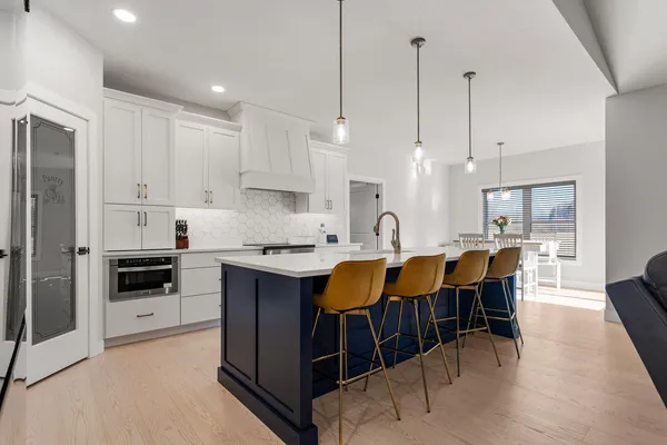 a large kitchen with kitchen island a dining table chairs and white cabinets
