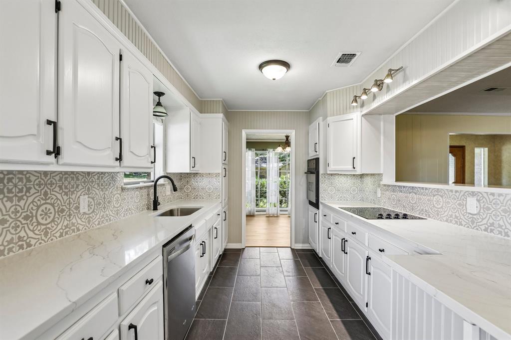 1600 South Timber Court Benbrook, TX 76126 - Photo 12 of 30 Galley kitchen featuring white cabinetry with matte black hardware, light-toned countertops, and decorative tile backsplash