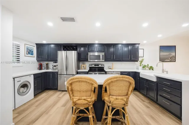 a kitchen with a refrigerator a microwave a sink and chairs