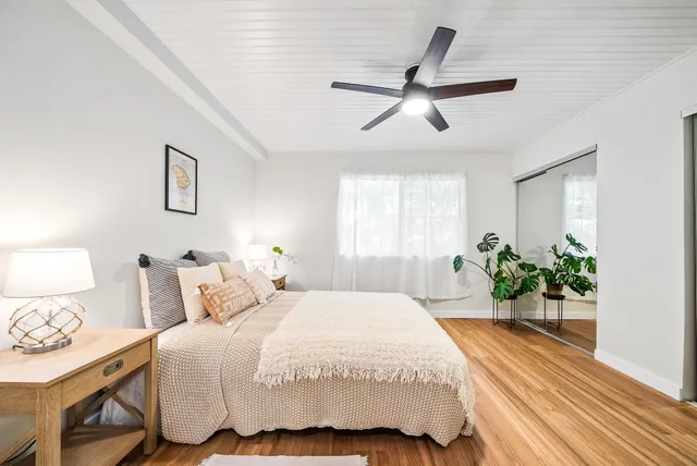 a bedroom with a bed a dresser and potted plants