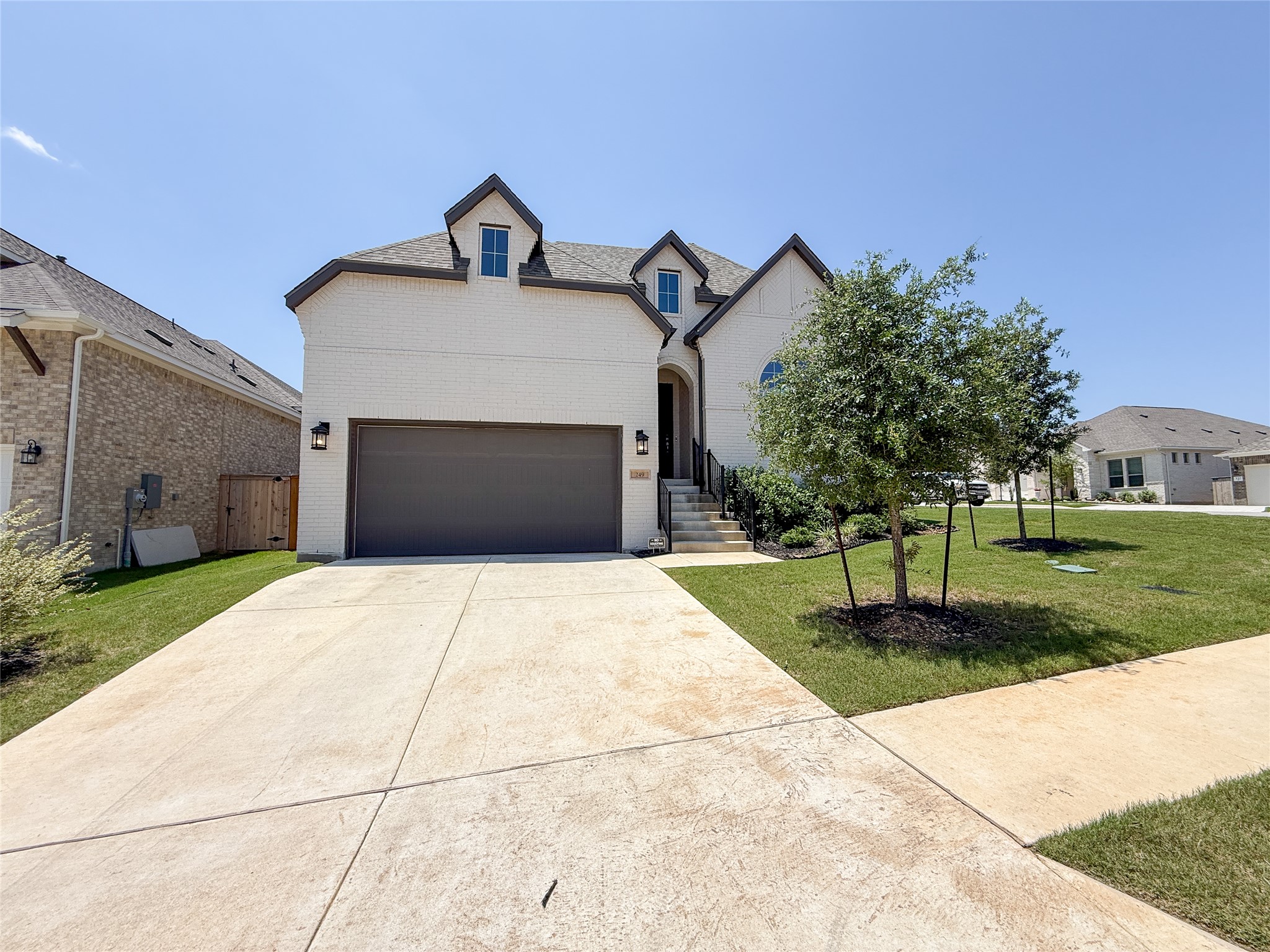 249 Heartleaf Road San Marcos, TX 78666 - Photo 3 of 38 A striking white brick facade welcomes you, accented by dormer windows and a verdant front lawn.