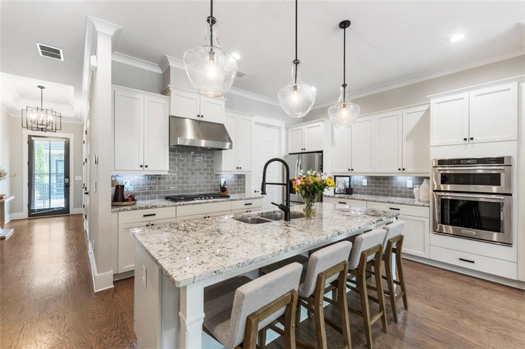 1909 Red Eagle Walk Atlanta, GA 30318 - Photo 12 of 61 a kitchen with stainless steel appliances granite countertop a stove a sink a microwave a dining table and chairs with wooden floor
