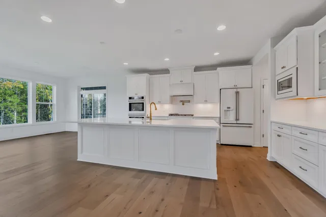 a large kitchen with stainless steel appliances a large counter top a stove and a wooden floors