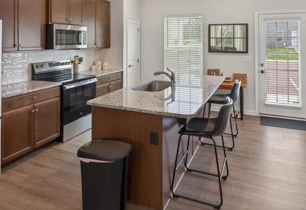 a kitchen with stainless steel appliances granite countertop a stove top oven a sink dishwasher and microwave oven with wooden floor