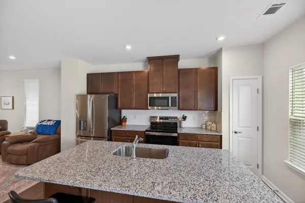a kitchen with kitchen island granite countertop a refrigerator and a stove top oven