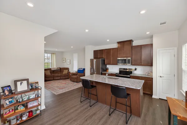 a kitchen with stainless steel appliances a stove a refrigerator a sink dishwasher with a dining table and chairs with wooden floor