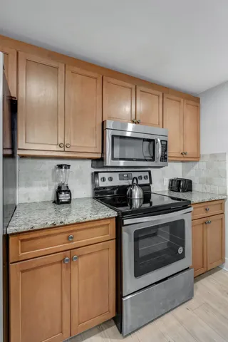 a kitchen with stainless steel appliances granite countertop a stove a sink and a microwave